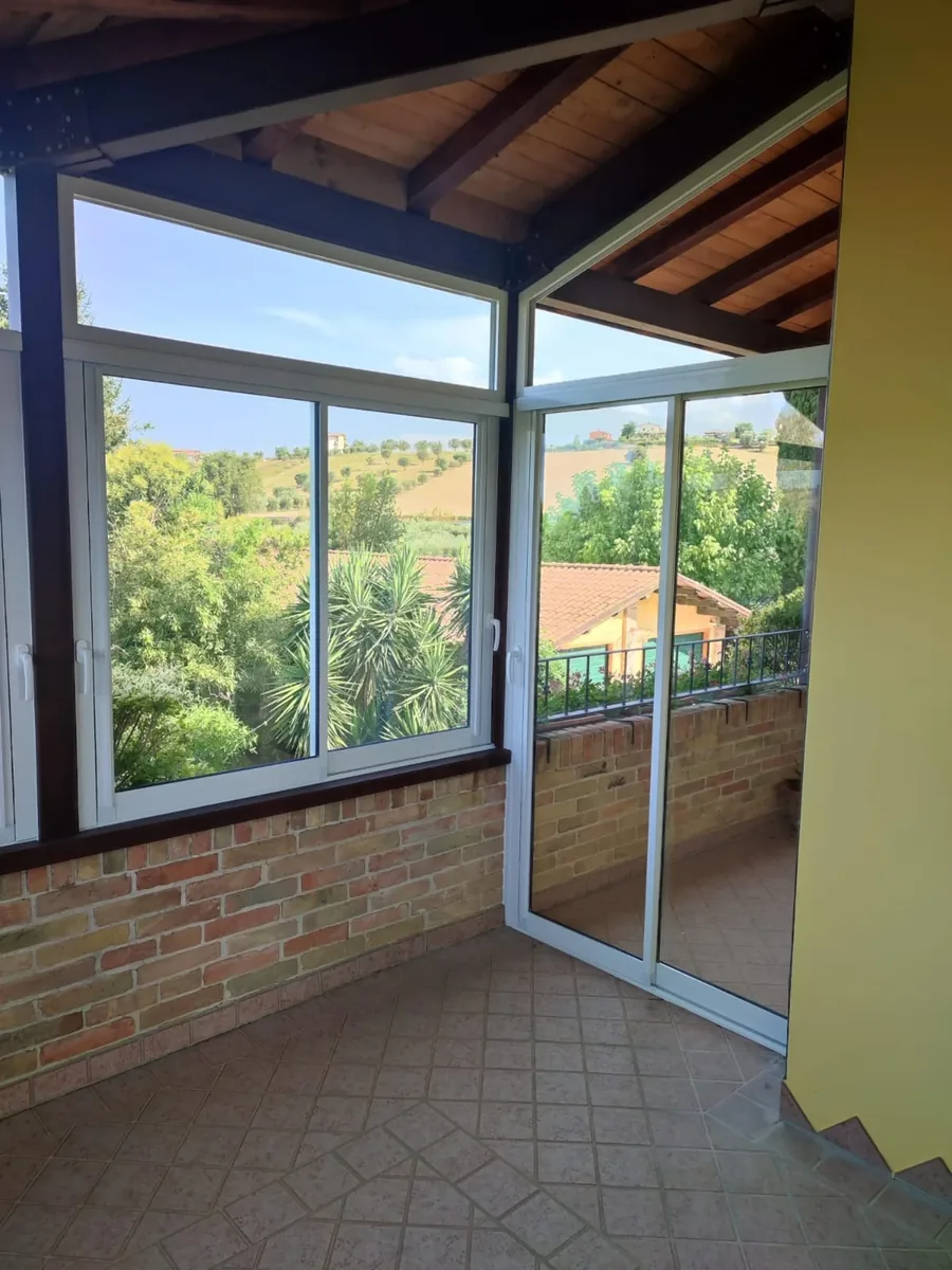 Veranda chiusa con finestre scorrevoli in alluminio bianco e vista panoramica sulle colline — IS Metal srl